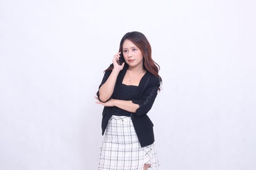 beautiful Indonesian woman 20s formal office smiling on the phone with her black cellphone gadget and carrying a tablet for promo isolated white background photo