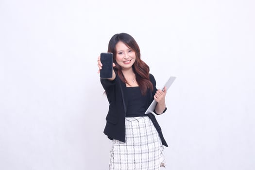 beautiful southeast asian woman 20s formal office big smile looking at cell phone gadget screen in front and carrying tablet for promo isolated white background photo