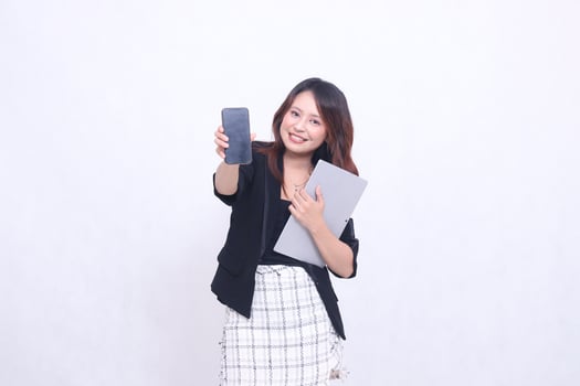 Beautiful Southeast Asian woman 20s formal office cheerful smile looking at cellphone gadget screen and carrying tablet for promo isolated white background photo