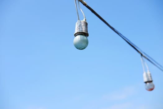 Equipped and electrical with light bulbs is hanging in the wind and sunlight on blue sky photo