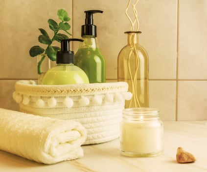 A table in the bathroom with cosmetics, accessories, a towel and a lit aroma candle photo