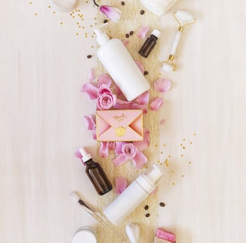 Romantic still life with cosmetics bottles, accessories, a gift box and rose petals on white background photo