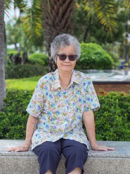 Portrait of happy elderly woman sitting in park photo