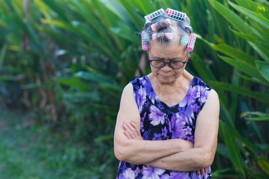 Portrait of an elderly woman hair curlers and looking down while standing in a garden. photo