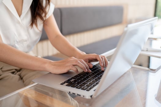 A close-up image of a woman working on her laptop computer, typing on the keyboard. photo