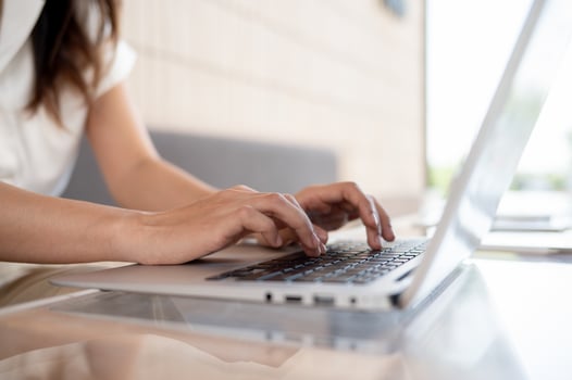 A close-up image of a woman working on her laptop computer, typing on the keyboard. photo