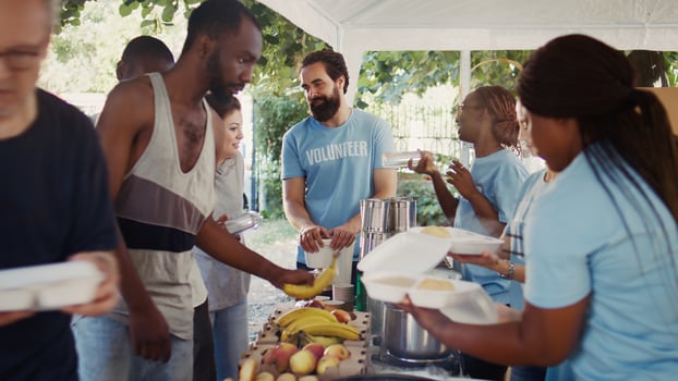 Voluntary individuals selflessly distribute free food to the needy, showing compassion and support in humanitarian charity event. Friendly volunteers offering hot meals and nourishments to the poor. photo