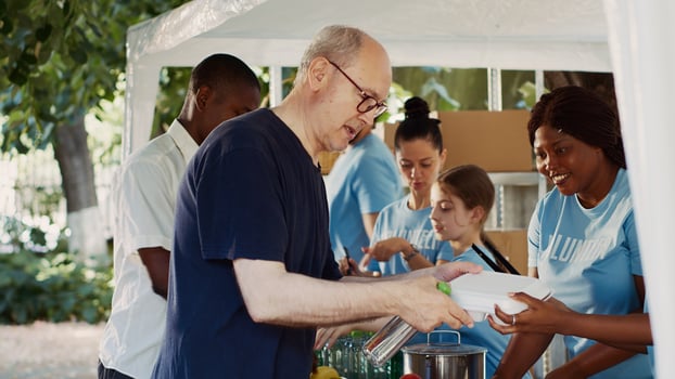 Friendly volunteers offering hunger relief to poor and needy individuals. People of different ethnicities who are less fortunate and homeless are fed by a charitable organization. Tripod shot. photo