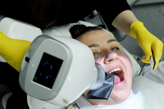 latest technology in dental clinic new x-ray scanner woman is taken picture after filling canals woman smiles pretty doctor yellow gloves special device for photography jaws of teeth and gums x-ray photo