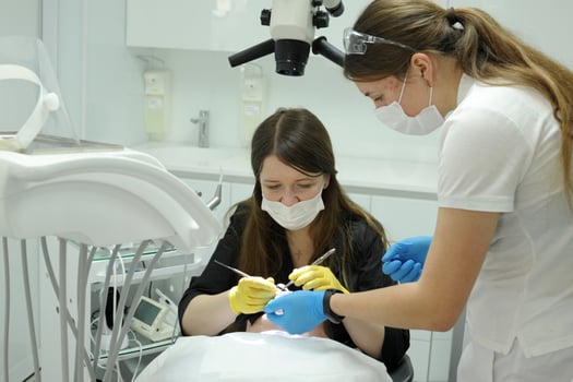 Close-up medical dentist procedure of teeth cleaning the doctor and the nurse bent over the patient, they treat the teeth, they fill the canals photo