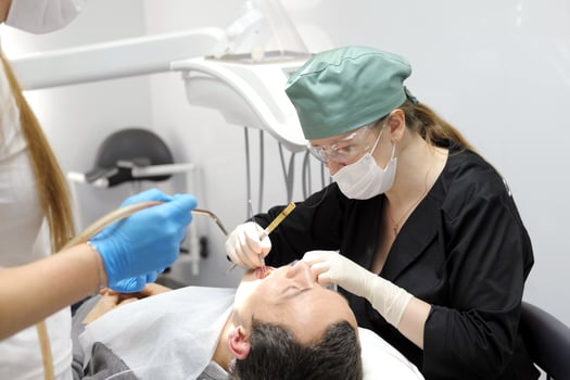 dentist professional filling teeth for man patient sitting in medical chair photo