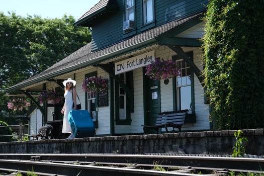 Travel alone girl with a large suitcase sits on a bench. Wait for the train white hat white dress summer photo
