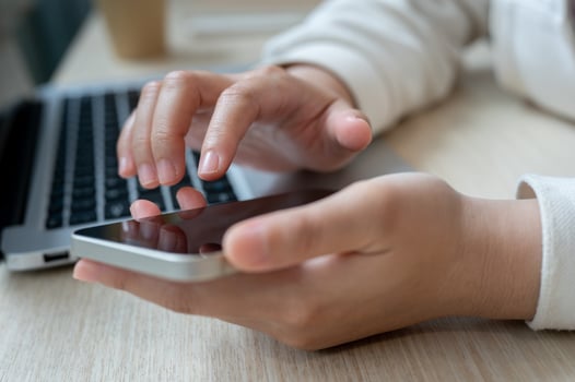 A close-up image of a woman touching on her smartphone screen, checking messages while working. photo