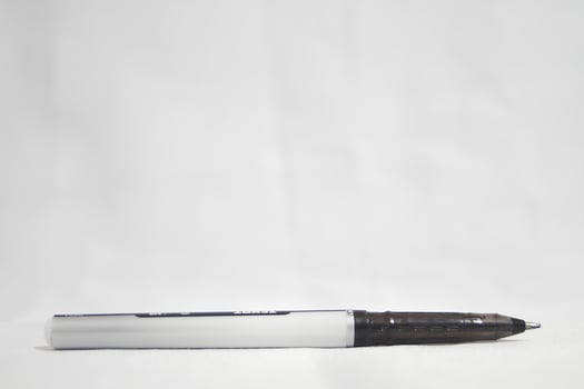 A black pen with a white tip sits on a white surface photo
