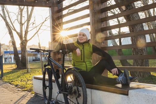 Woman Resting on a Park Bench After a Bicycle Ride at Sunset photo