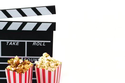 Clapperboard or movie slate black color with popcorn on white background. Cinema industry, production and film concept. photo