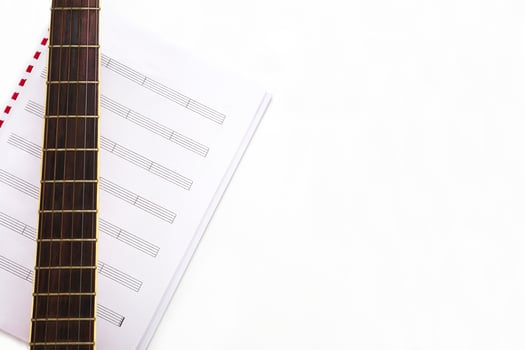 Focus the acoustic guitar neck and blur musical notes on white background. Love, music and learning concept. photo