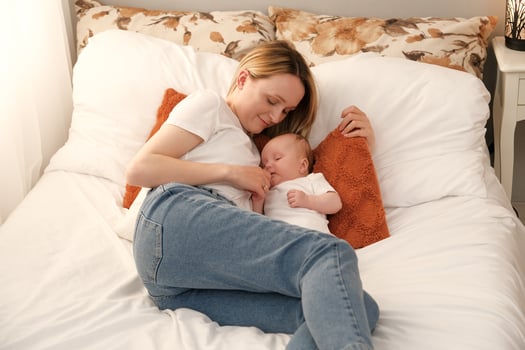 mom with a newborn baby lies on the bed. mother kisses the child. mother's love . photo