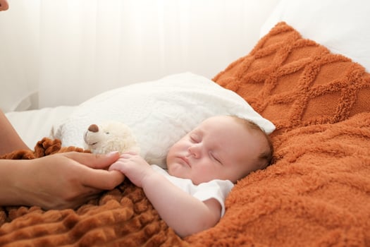 a newborn baby sleeps on a bed. A teddy bear lies nearby. mother and child. photo
