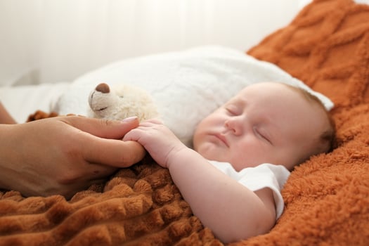a newborn baby sleeps on a bed. A teddy bear lies nearby. mother and child. photo