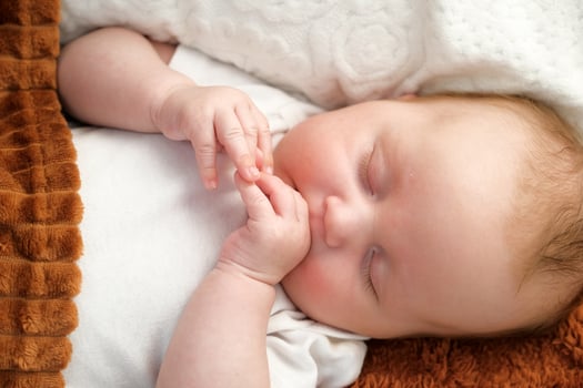 a newborn baby sleeps on a bed. A teddy bear lies nearby. mother and child. photo