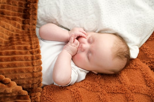 a newborn baby sleeps on a bed. A teddy bear lies nearby. mother and child. photo