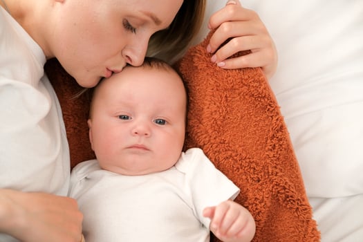 mom with a newborn baby lies on the bed. mother kisses the child. mother's love . photo