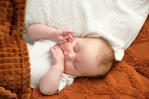 a newborn baby sleeps on a bed. A teddy bear lies nearby. mother and child. photo