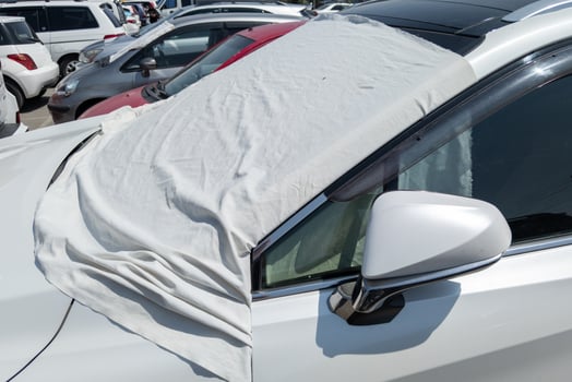 car windshield is covered with white bedsheet to prevent heating on a parking lot at hot sunny summer day in Asia photo