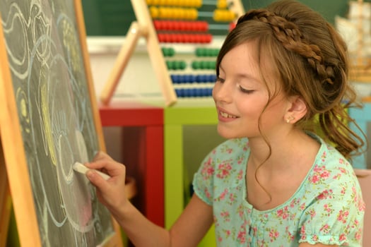 Sweet little girl learning happily in front of her blackboard photo