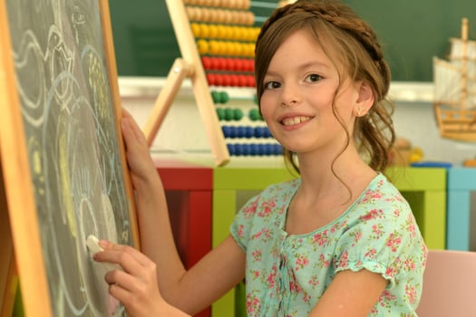 Sweet little girl learning happily in front of her blackboard photo