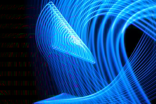Long exposure light painting curvy lines of vibrant neon metallic blue on black background. photo