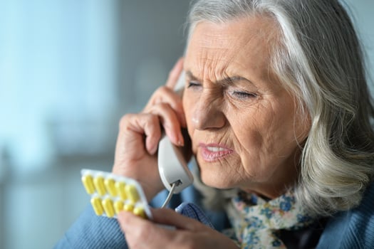 Portrait of sick senior woman calling with phone photo