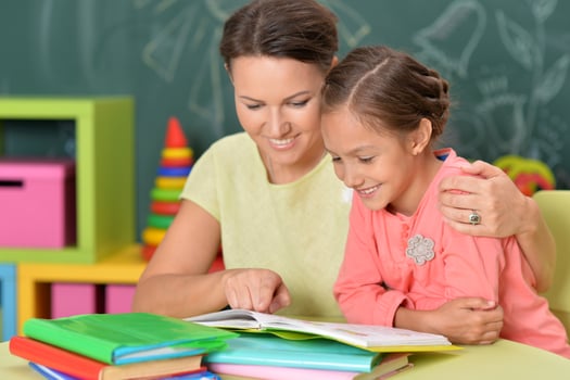 Portrait of little girl with her mother doing homework photo