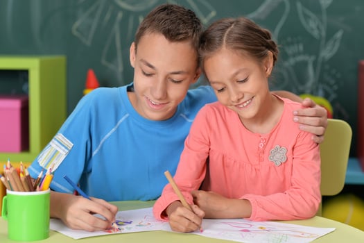 A brother and sister drawing sitting at a table photo