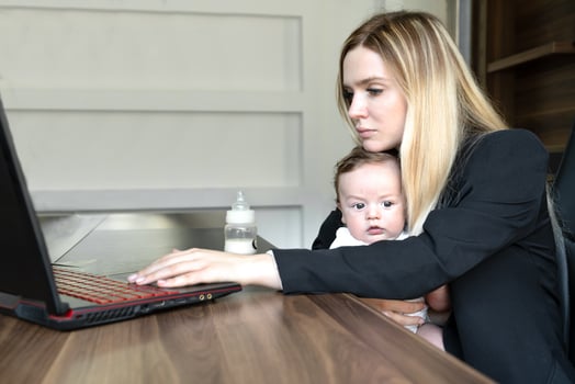 Young woman holds baby in her arms, in office, combining this with working on laptop., concept of combining business and caring for newborn baby photo