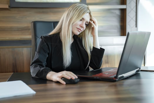 Focused girl blonde in black suit is sitting front of laptop in office, concept of online education and work. photo