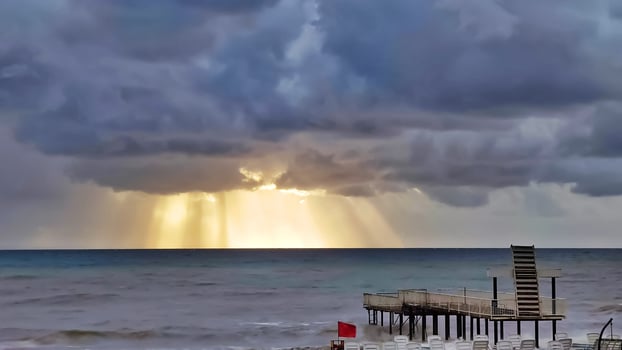 Stormy sea and dark blue clouds with gaps sun's rays, view from shore. photo