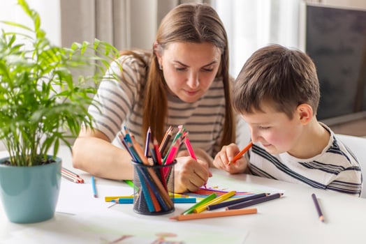 Mother and child drawing with pencils sitting at the desk at home photo
