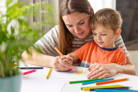 Mother and child drawing with pencils sitting at the desk at home photo