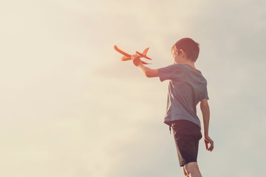 Little boy launches a toy plane into the air. Child launches a toy plane photo