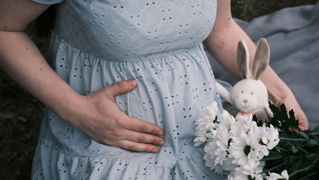 A pregnant woman holding her belly, close-up photo