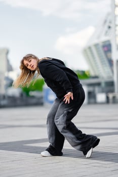 A young woman wears oversized clothes and dances hip-hop. photo
