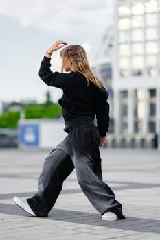 A young woman wears oversized clothes and dances hip-hop. photo