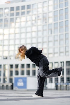 A young woman wears oversized clothes and dances hip-hop. photo