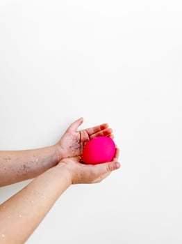 Hands holding a pink egg with glitter, Easter preparation and festive activity concept on a white background with copy space. For Easter themed creative content, and family activity ideas. photo