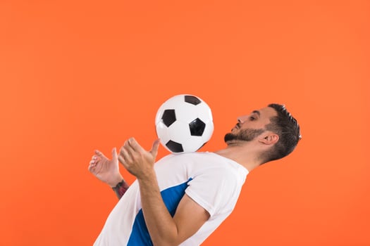 Professional Football player playing with ball isolated on orange background photo