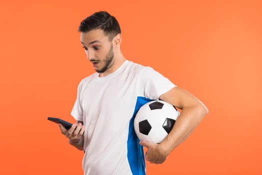 Football fan or player looking at smartphone Surprised and holding a football under arm photo