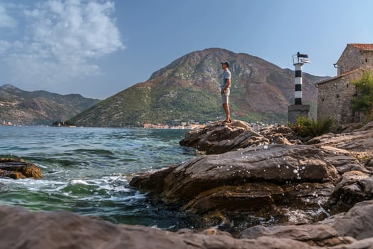 Man Tourists Standing on Cliff near Lighthouse in Montenegro photo