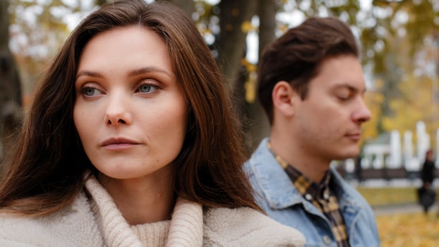 Caucasian girl offended by male lover on background young family couple standing outdoors ignoring each other looking different ways conflict misunderstanding sad woman thinking breakup with boyfriend photo